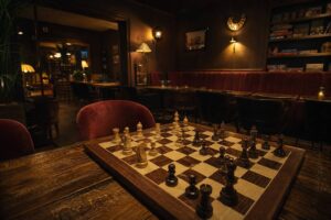 Échiquier en bois sur table dans un bar à jeux parisien à l'ambiance tamisée
